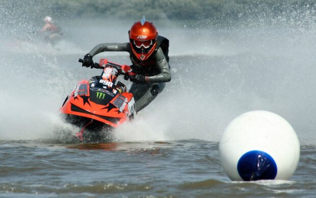 A person wearing a helmet is riding a jet ski at high speed on the water, HD Desktop Wallpaper