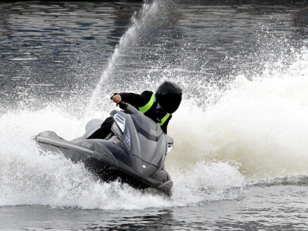 A person wearing a helmet rides a jet ski making a sharp turn on the water, HD Desktop Wallpaper