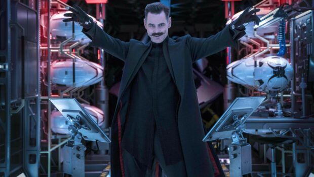 Jim Carrey stands confidently with arms raised in a high tech room, 4K Desktop Wallpaper