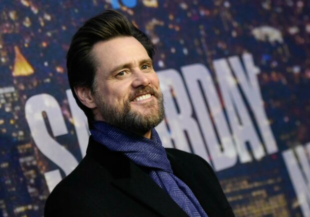 Jim Carrey smiles warmly at a public event with a patterned scarf and dark coat, 2K Desktop Wallpaper