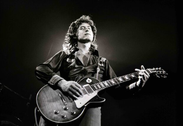 Jimmy Page playing guitar on stage during a live rock performance