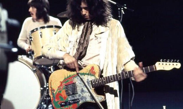 Jimmy Page playing guitar with a bow during a live performance on stage
