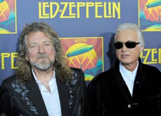 Jimmy Page stands with a man in front of a Led Zeppelin poster at an event