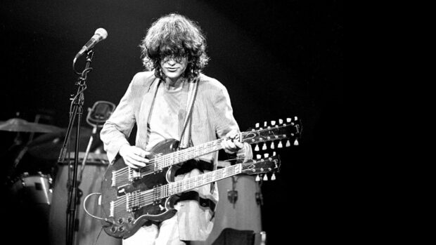 Jimmy Page playing a double neck guitar on stage with a microphone nearby