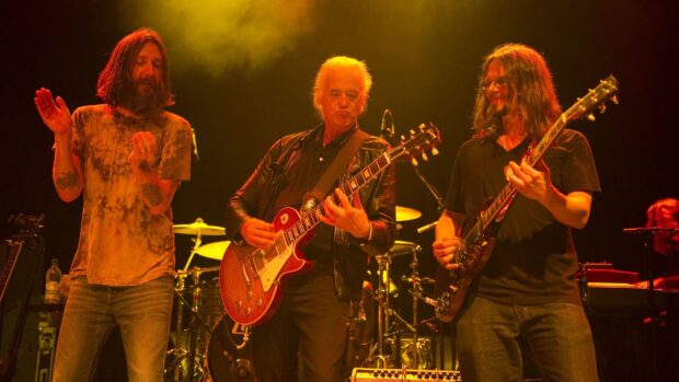 Jimmy Page playing guitar on stage with band members during a live concert performance