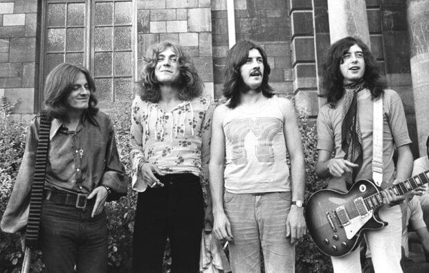 Jimmy Page with his band members standing outside a building in a vintage black and white photo