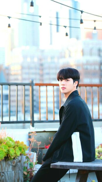 Jin BTS wallpapers show him sitting on a rooftop bench wearing a black jacket, HD Phone Wallpaper