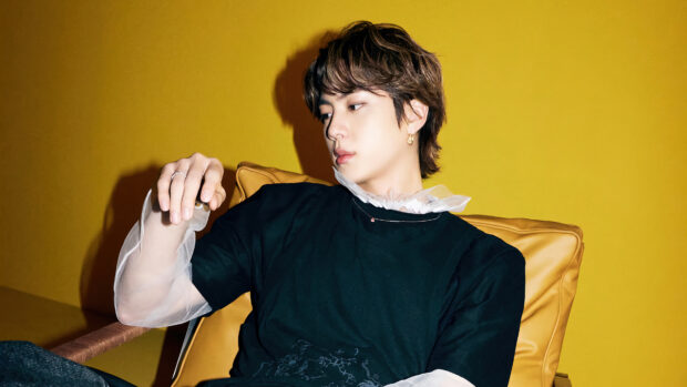 Jin BTS is sitting on a yellow chair wearing a black shirt with sheer sleeves, 4K Desktop Wallpaper