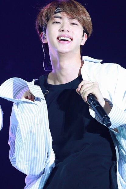 Jin BTS Wallpapers is captured smiling and holding a microphone on stage, HD Phone Wallpaper