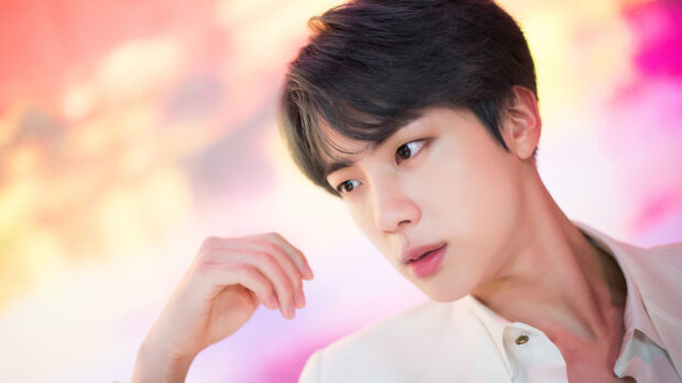 Jin BTS looks thoughtful against a colorful backdrop, 4K Desktop Wallpaper