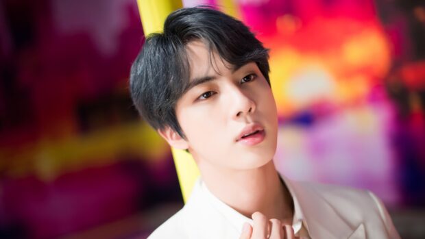 A close up of Jin from BTS with a vibrant and colorful backdrop, 2K Desktop Wallpaper