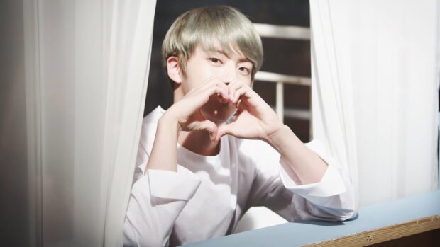 Jin Bts is making a heart shape with his hands near his face, HD Desktop Wallpaper