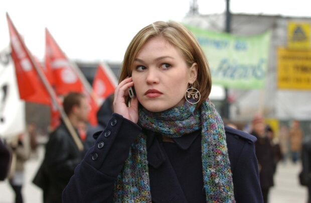 Julia Stiles is talking on the phone outdoors during a protest, 2K Desktop Wallpaper
