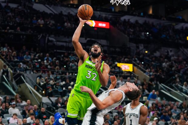 Karl Anthony Towns jumping for a basketball in a game wearing a Minnesota jersey