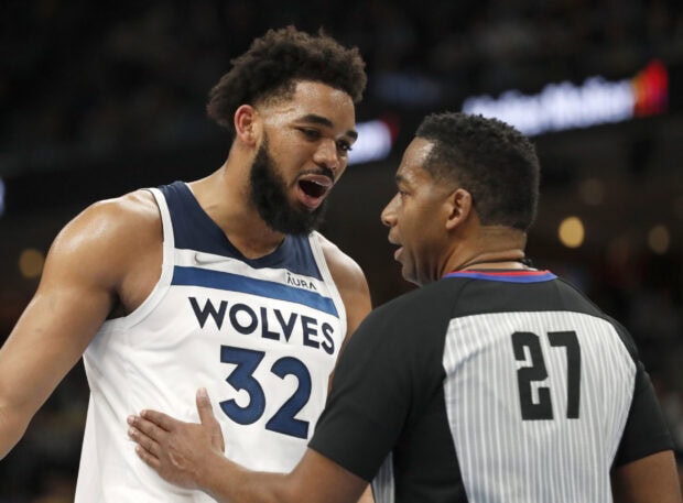 Karl Anthony Towns talking with a referee during a basketball game on the court