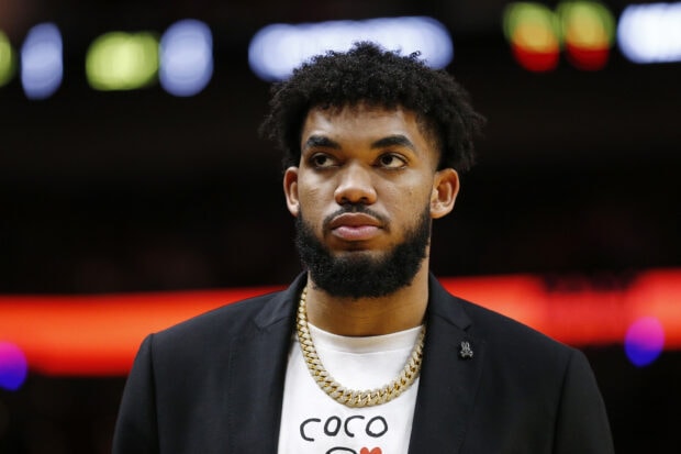 Karl Anthony Towns wearing a black blazer and gold chain looking away in a close up portrait