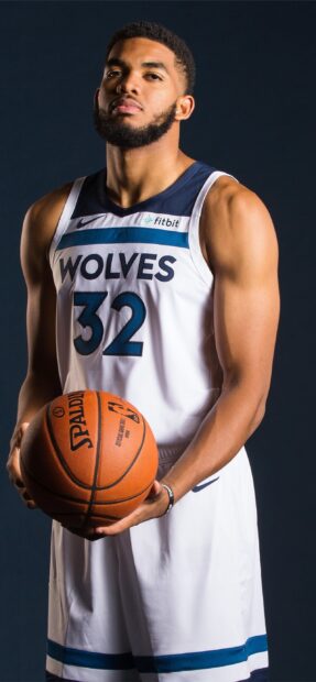 Karl Anthony Towns holding a basketball wearing a Wolves basketball jersey