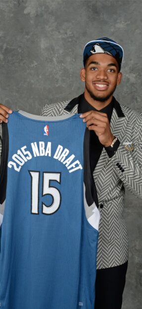 Karl Anthony Towns holding a 2015 NBA draft jersey showing the number 15
