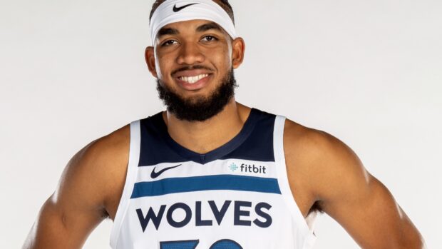 Karl Anthony Towns posing in a Wolves jersey with a white headband and friendly smile