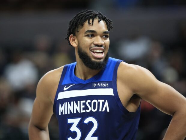 Karl Anthony Towns wearing a Minnesota basketball jersey smiling during a game