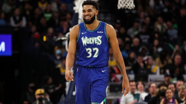 Karl Anthony Towns smiling on the court wearing a Wolves jersey with number 32