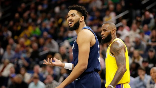 Karl Anthony Towns talking to a teammate during an NBA game with a crowded arena background