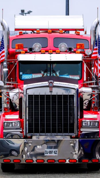 A red Kenworth truck is parked with visible American flags on both sides, 4K Mobile Wallpaper