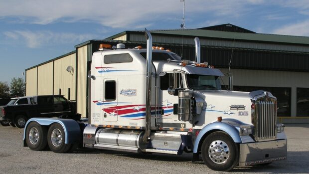 A Kenworth truck with red and blue star decals parked outside a garage, HD Desktop Wallpaper