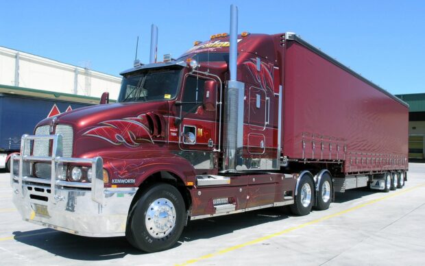 A red Kenworth truck stands parked under a clear blue sky, HD Desktop Wallpaper