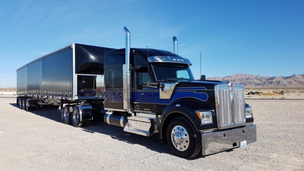 A Kenworth truck is parked on a dry desert area with mountains in the background under a clear blue sky, HD Desktop Wallpaper