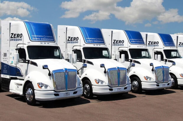 Kenworth trucks with zero emissions are lined up under a cloudy sky, HD Desktop Wallpaper