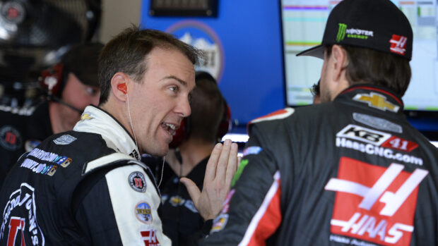 Kevin Harvick discussing race strategy with a team member in his racing suit, 4K Desktop Wallpaper