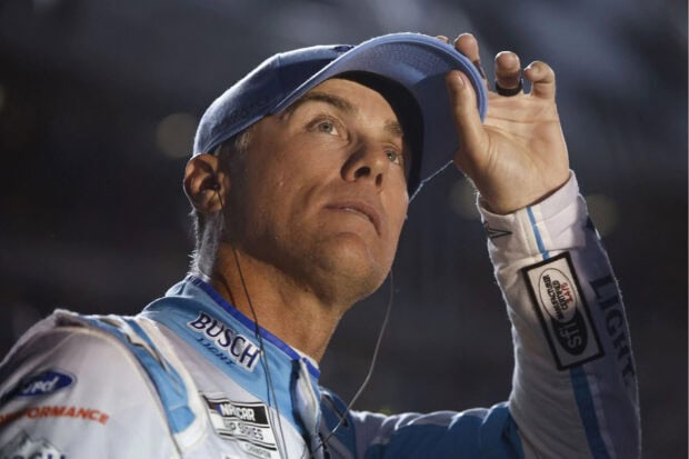 Kevin Harvick adjusts his cap while wearing a racing suit during a NASCAR event, HD Desktop Wallpaper