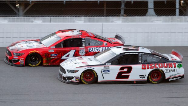 A red Kevin Harvick car speeds alongside another race car during a NASCAR event, 2K Desktop Wallpaper