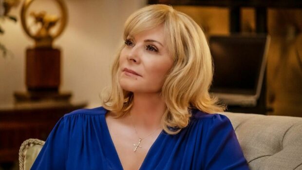 Kim Cattrall is wearing a blue dress and a cross necklace sitting on a couch, HD Desktop Wallpaper