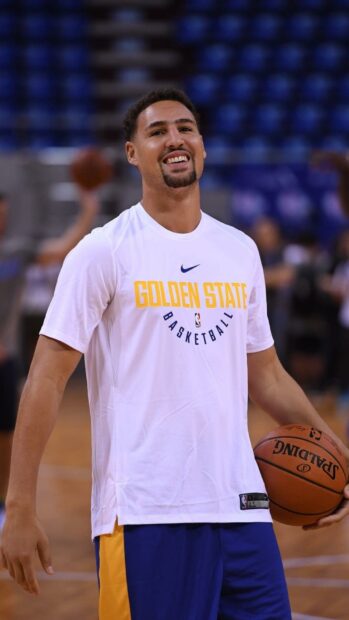Klay Thompson is smiling and holding a basketball on the court during practice, HD Mobile Wallpaper