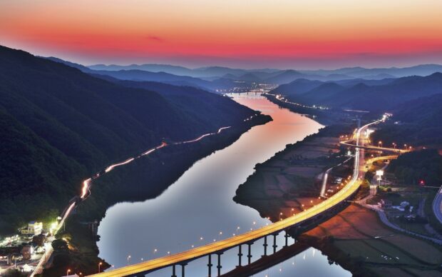 Serene river winding through mountains at sunset in Korea landscape
