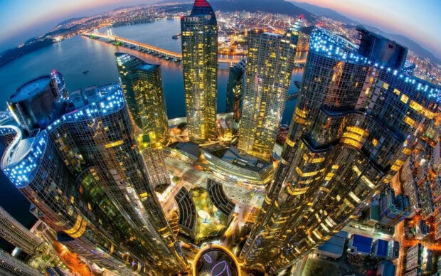 A stunning Korea cityscape showing modern skyscrapers and a long bridge over the river at night