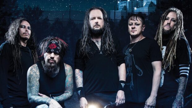 Korn band members with tattoos and dreadlocks posing together at night