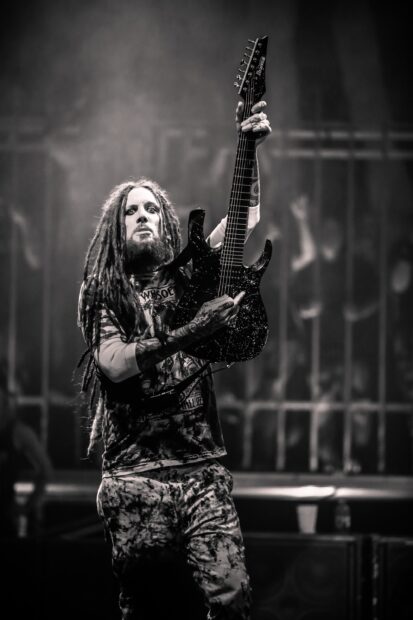 Rockstar with dreadlocks playing guitar at Korn concert on stage