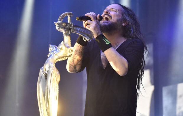 The lead singer of Korn passionately performing on stage with a decorative microphone stand