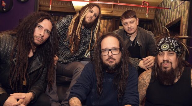 Korn band members posing together indoors with music themed background