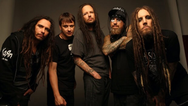 Korn band members posing together with long dreadlocks and tattoos in a studio setting
