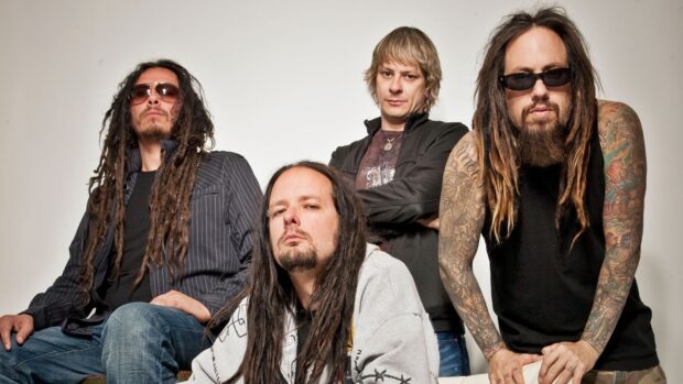 Korn band members posing together with long hair and tattoos in a studio setting