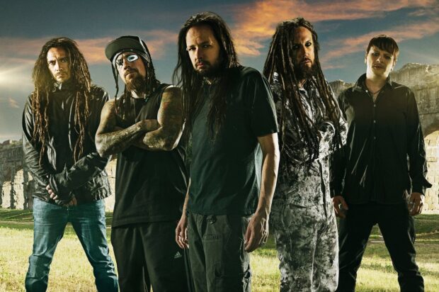 Korn band members standing outdoors with a dramatic sky in the background