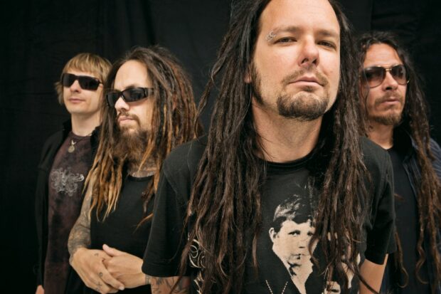 Korn band members with dreadlocks and sunglasses posing together in a studio setting