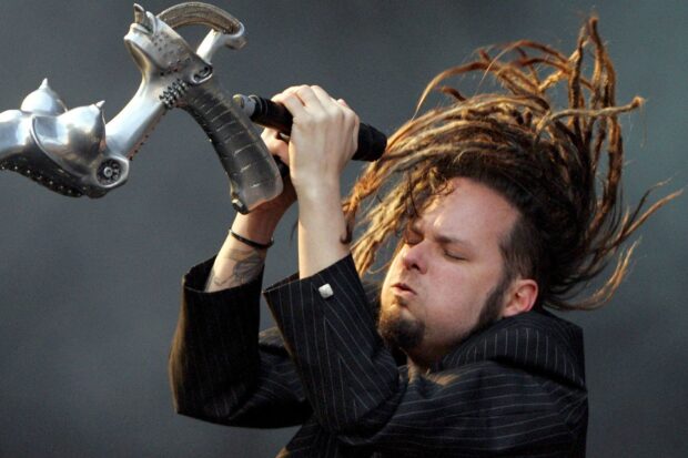Korn musician performing passionately with dreadlocks and unique microphone on stage