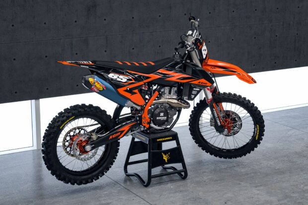A detailed KTM dirt bike with orange and black design on a stand in a modern garage