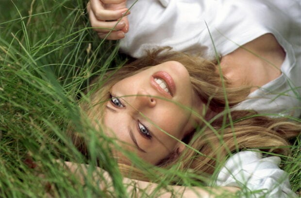 Kylie Minogue lying down with a gentle expression surrounded by grass, HD Desktop Wallpaper