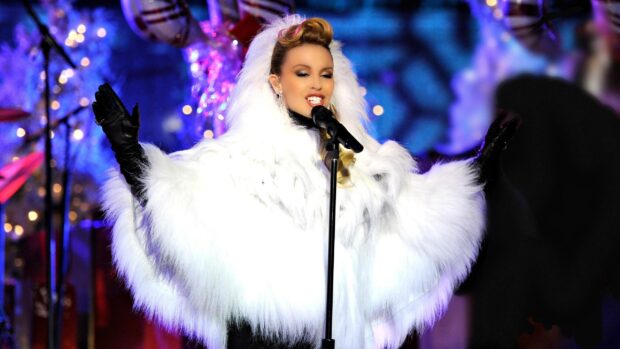 Kylie Minogue performs passionately in a white fur coat and gloves at a live event, 2K Desktop Wallpaper